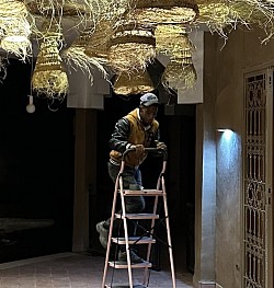 Assan jeune électricien qui a réalisé l’installation du plafond lumineux avec ses 45 lampes en paille, apportant une touche unique à l’ambiance du lieu